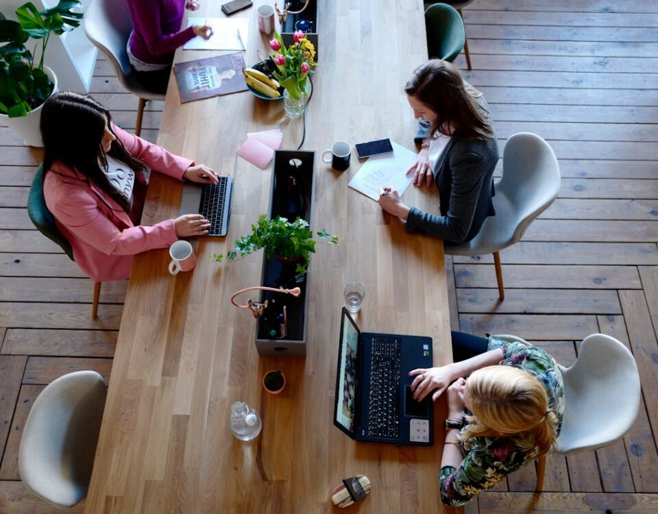 Three Woman Sitting on White Chair in Front of Table