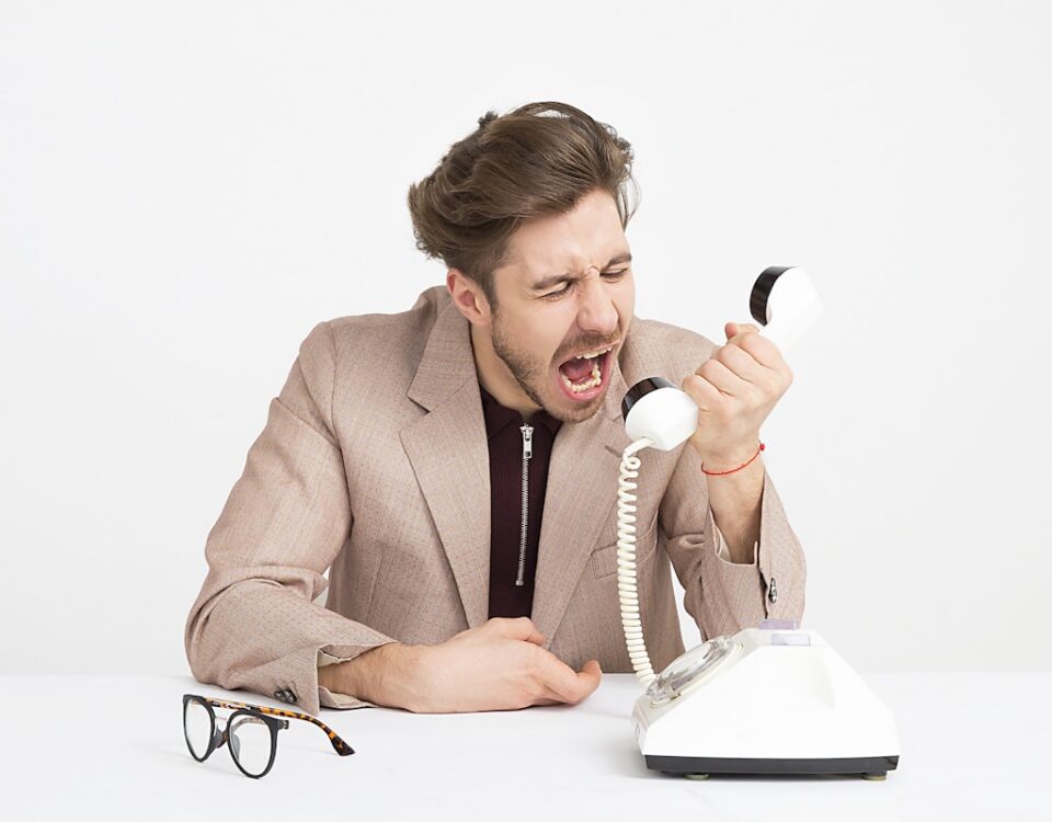 O impacto legal de avaliações online difamatórias para empresas man holding telephone screaming