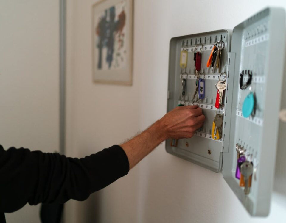 A responsabilidade legal do síndico profissional em condomínios A man arranges keys in a wall-mounted cabinet inside an office setting.