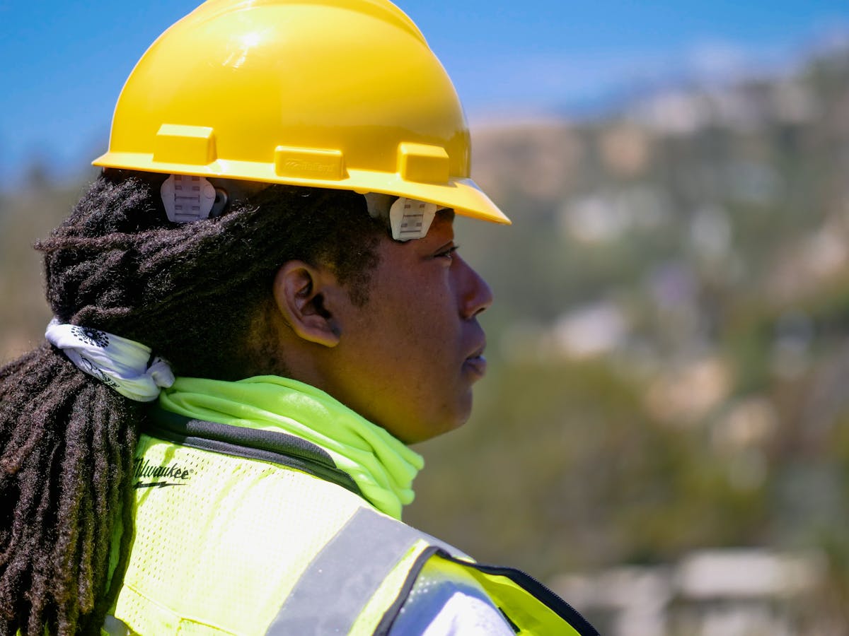 Uniforme NR10: O que a Legislação Diz Professional female engineer wearing safety gear and hardhat at a construction site outdoors.