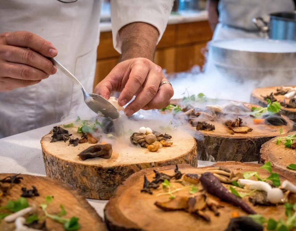 Regulamentações que afetam a produção de alimentos artesanais A chef artfully plating a gourmet dish with mushrooms and greens on wood slices.