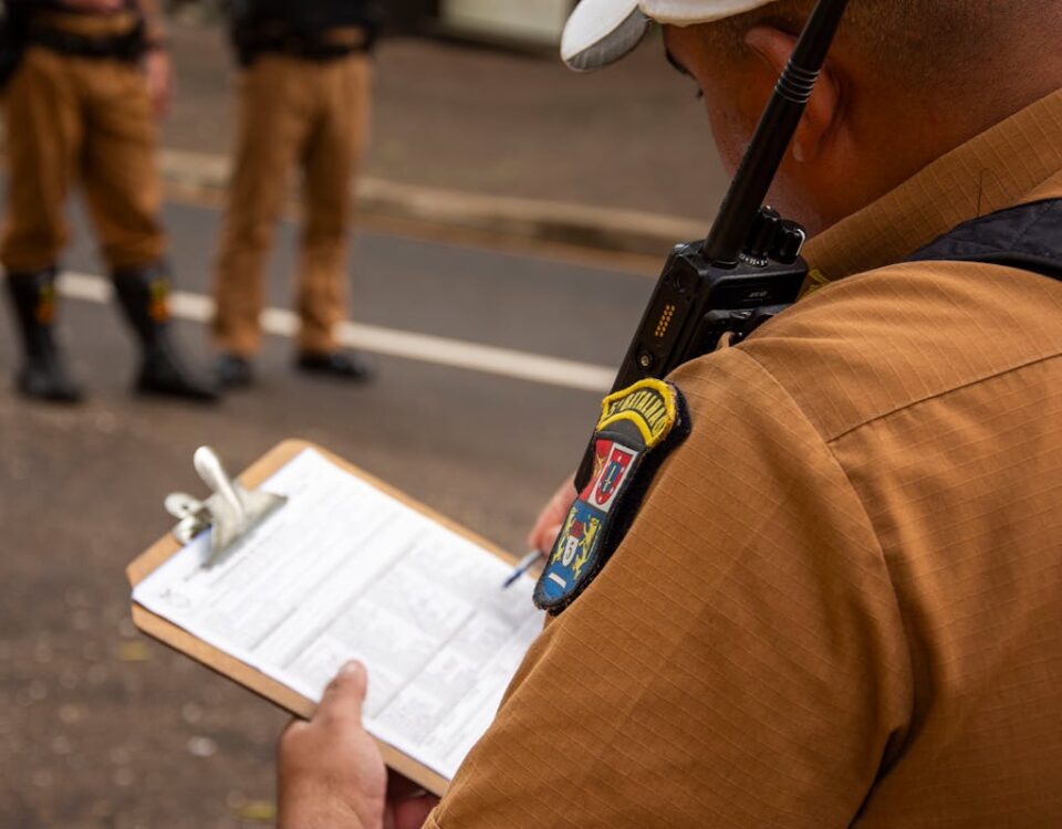 Close-up of a police officer writing on a clipboard outdoors in Londrina, Brazil.