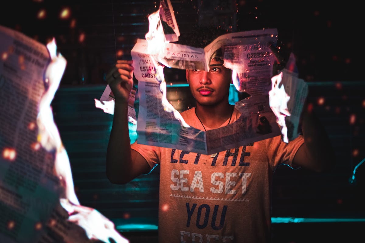 A young man holding a burning newspaper, creating a dramatic and intense atmosphere.