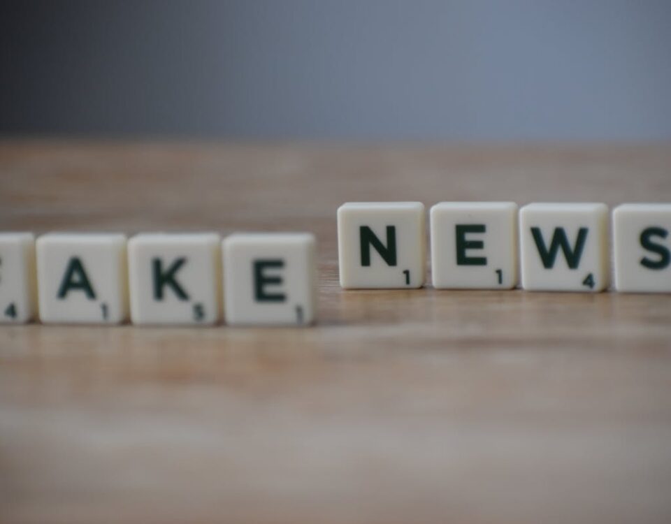 Fake news: quais são as implicações legais? Scrabble tiles spelling 'Fake News' on a wooden surface highlighting misinformation.