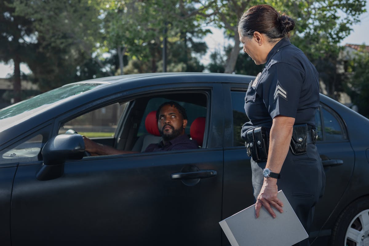 A policewoman discusses a traffic violation with a driver on a sunny day.