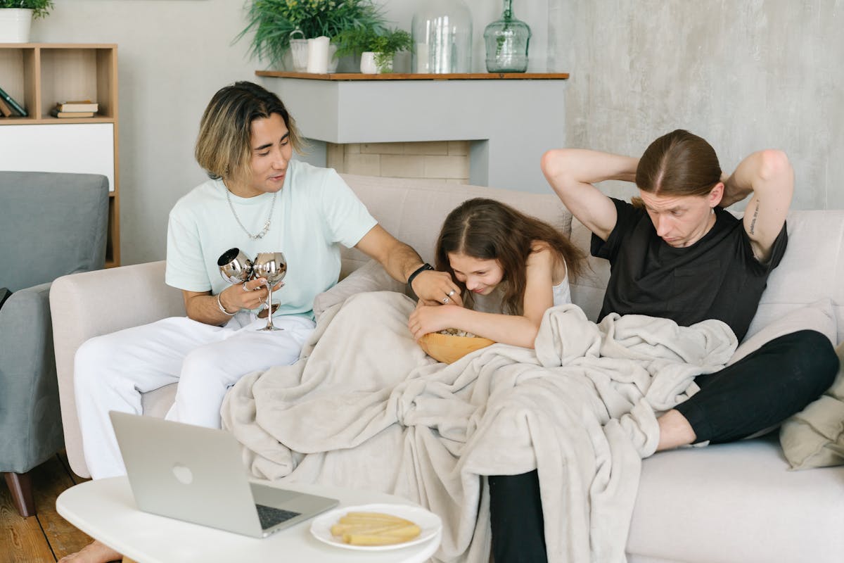 A family enjoying movie time on the couch with snacks and a laptop.