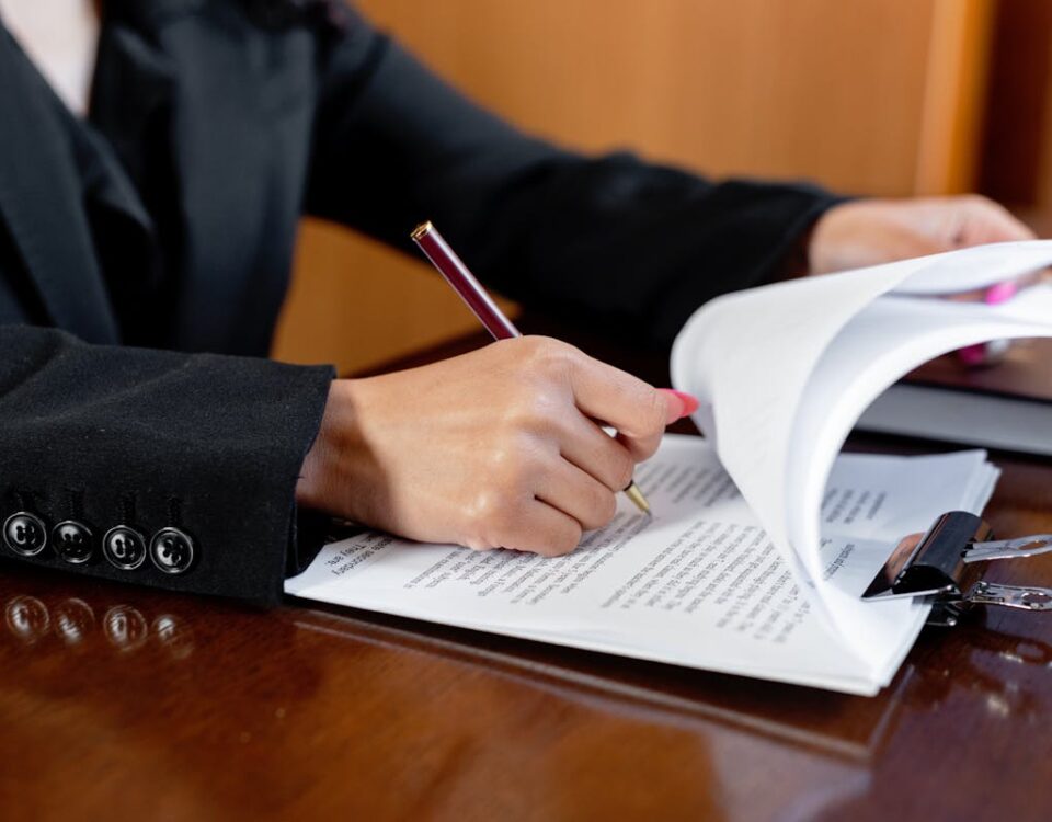 Direito à saúde: Quando contratar um advogado especializado Close-up of a woman signing legal documents with a pen in an office setting.