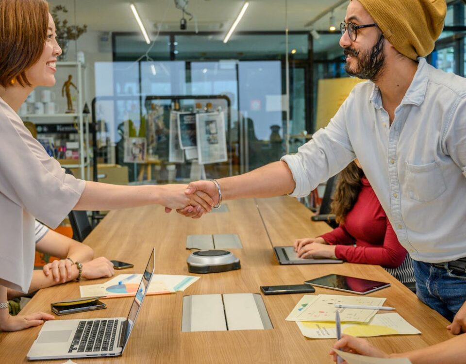 O que revisar em contratos com agências criativas? Diverse team in a modern office engaged in a collaborative meeting, sealing a partnership with a handshake.