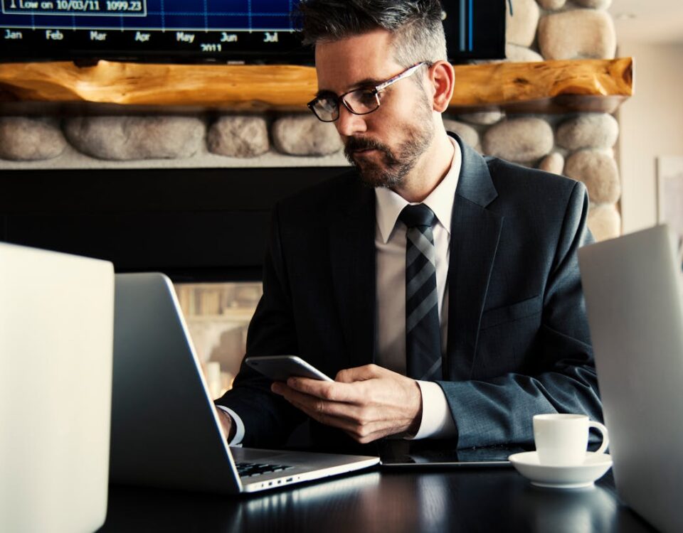 Prazo é essencial: Quando acionar o advogado no plano de saúde? Businessman in formal attire working on a laptop and smartphone at an indoor office desk.