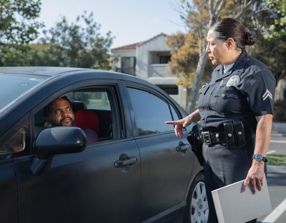 A police officer interacts with a driver during a daytime traffic stop on a residential street.