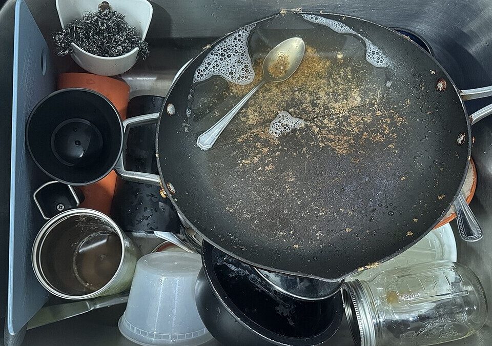 Pia de cozinha cheia de panelas, copos e louça suja