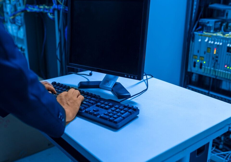 Técnico em sala de servidores digitando em computador