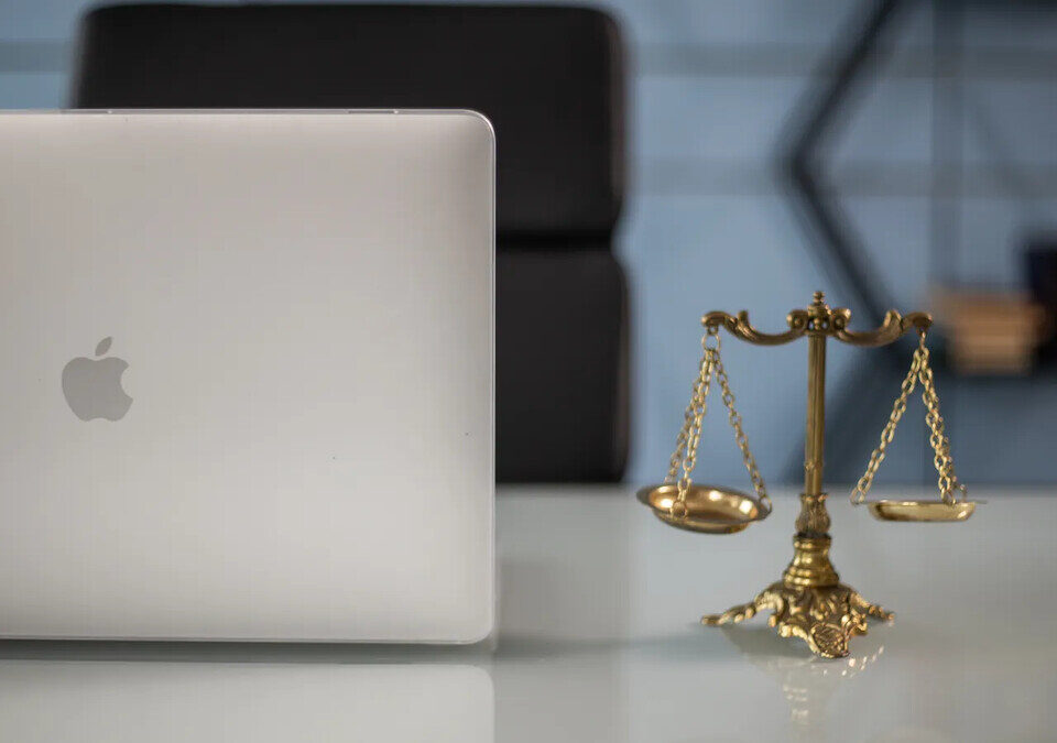 Balança da justiça ao lado de um notebook em mesa de escritório