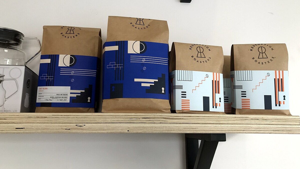 Café artesanal online: o que o rótulo precisa informar? Pacotes de café de torrefação dispostos em prateleira de madeira
