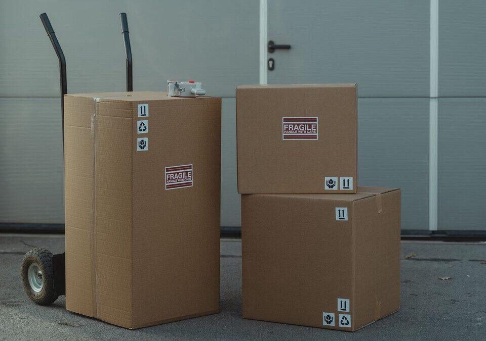 Caixas de papelão de encomenda empilhadas ao lado de um carrinho de carga