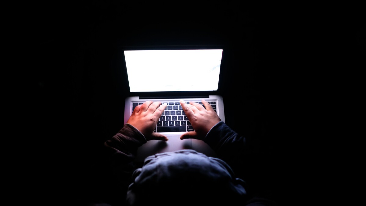Pessoa usando um notebook em ambiente escuro durante uma atividade online.
