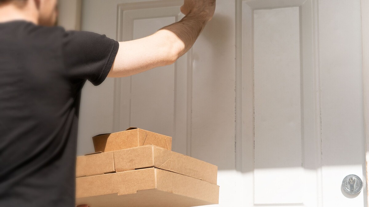Comprou produto desviado em marketplace? Quem responde e como agir Entregador batendo na porta de uma casa segurando caixas de papelão