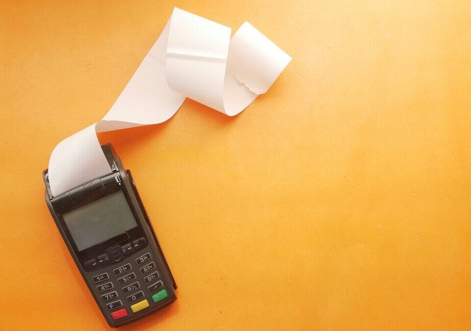Terminal de pagamento com recibo de papel branco sobre fundo laranja