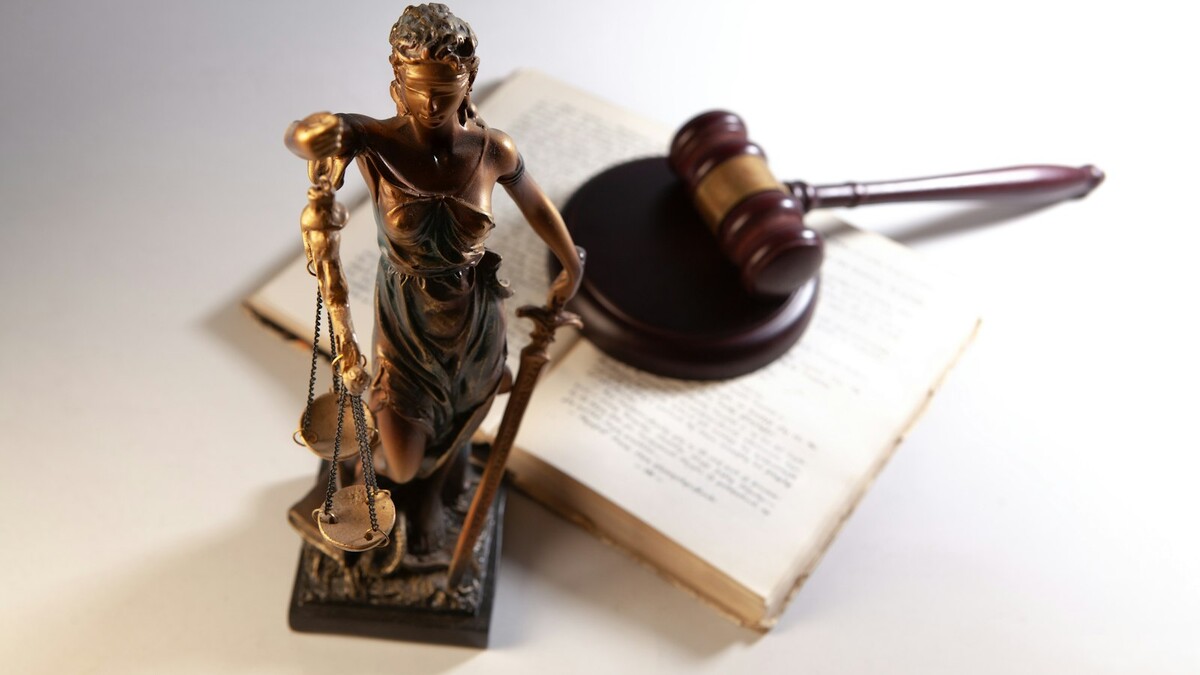 Estátua da deusa da justiça com martelo de juiz sobre um livro aberto