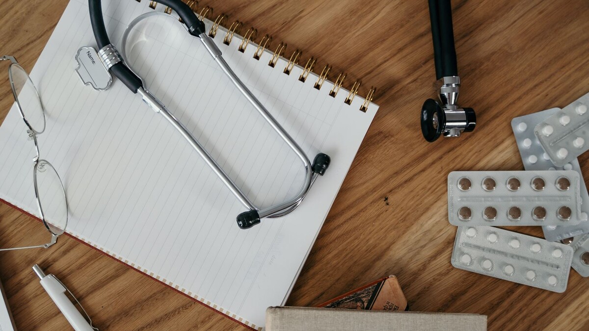 Exame demissional é obrigatório ou a empresa pode dispensar? Estetoscópio sobre um caderno aberto em uma mesa de madeira