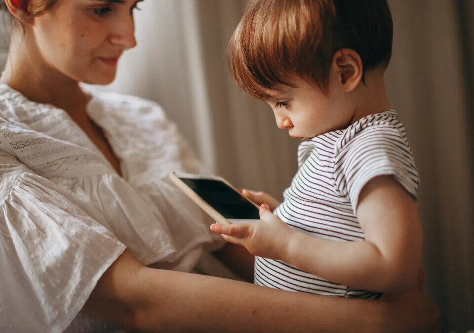 Mãe e criança observando smartphone em casa