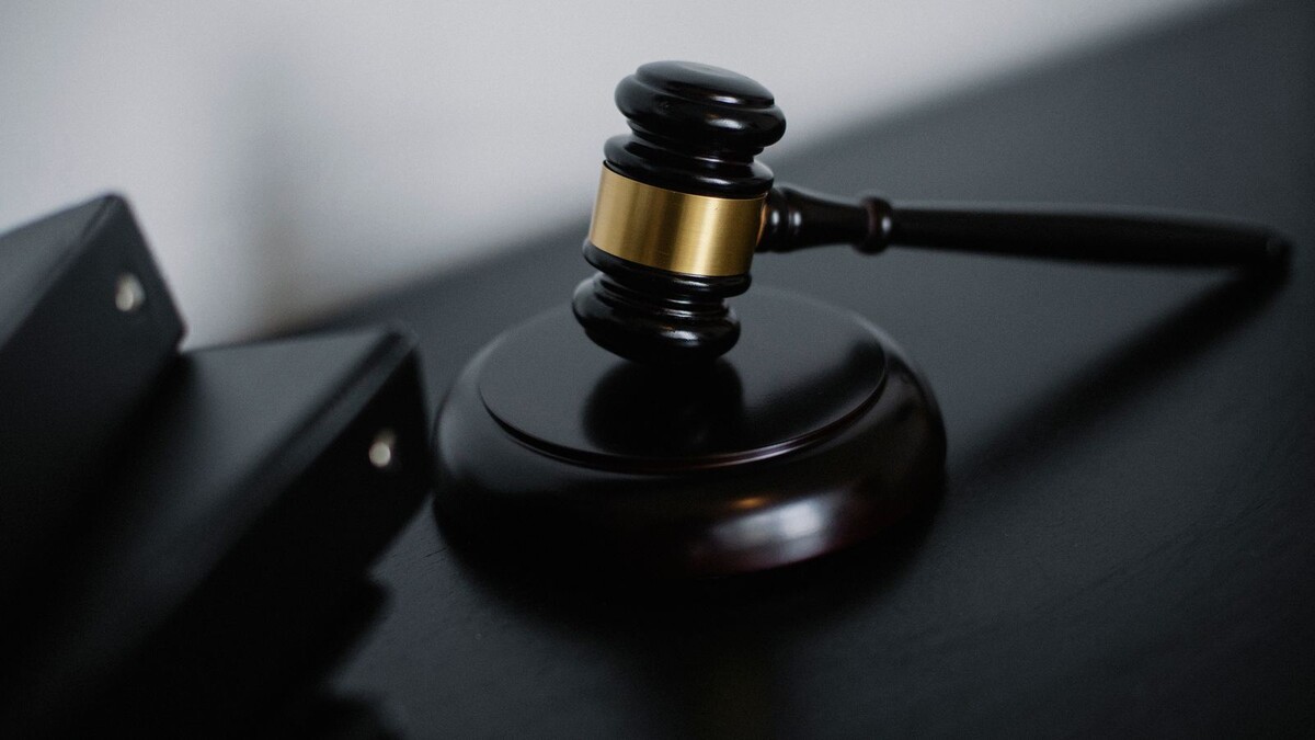 Lei Antifacção: o que mudou nas penas e na progressão de regime Martelo de juiz sobre mesa ao lado de pastas de processos