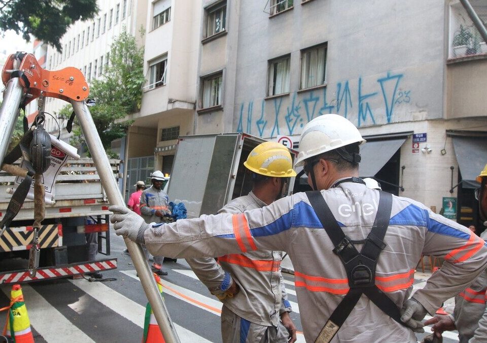Equipe de eletricistas com capacetes trabalhando em rua de São Paulo