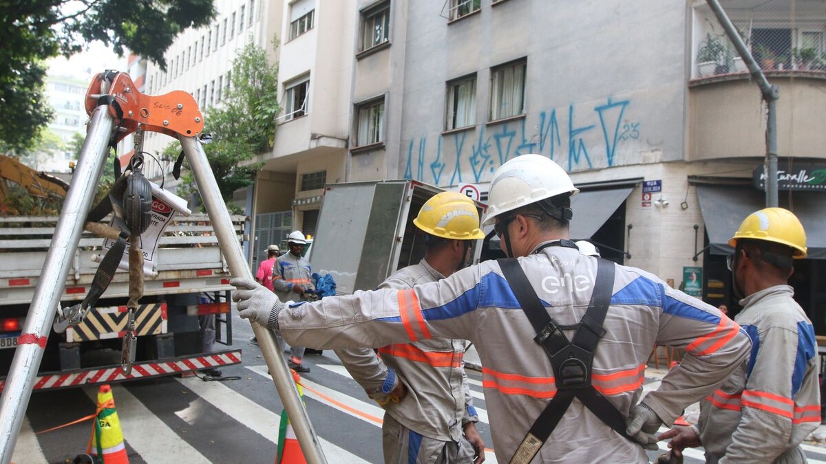 Equipe de eletricistas com capacetes trabalhando em rua de São Paulo