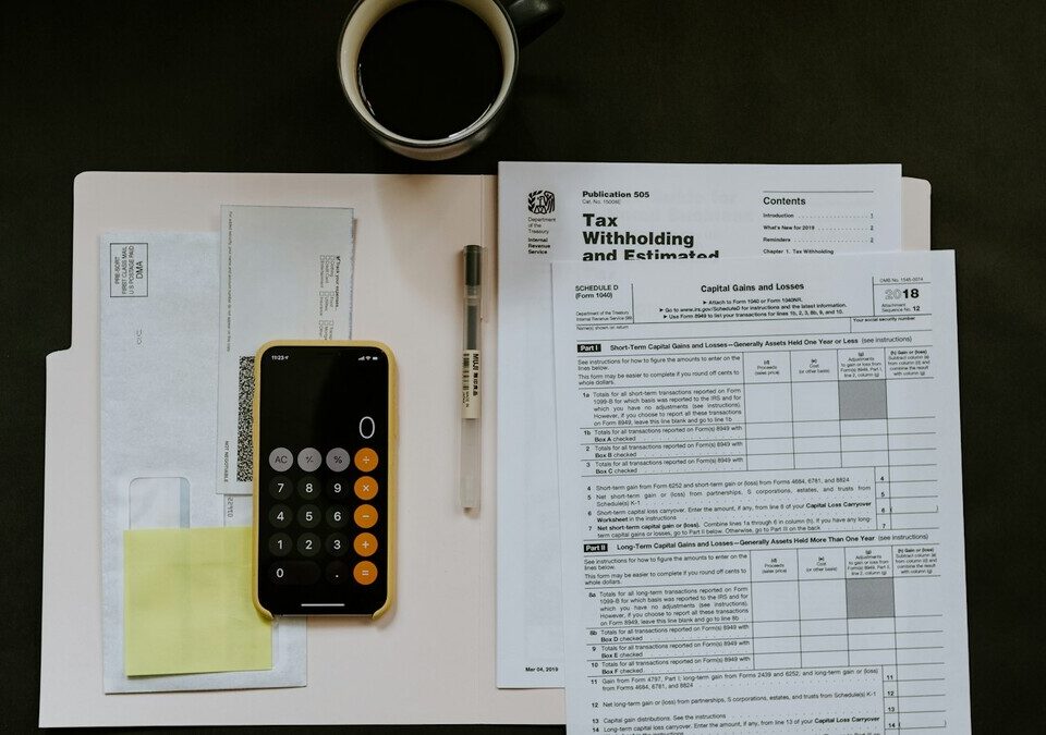 Documentos fiscais, celular com calculadora e caneta sobre uma mesa