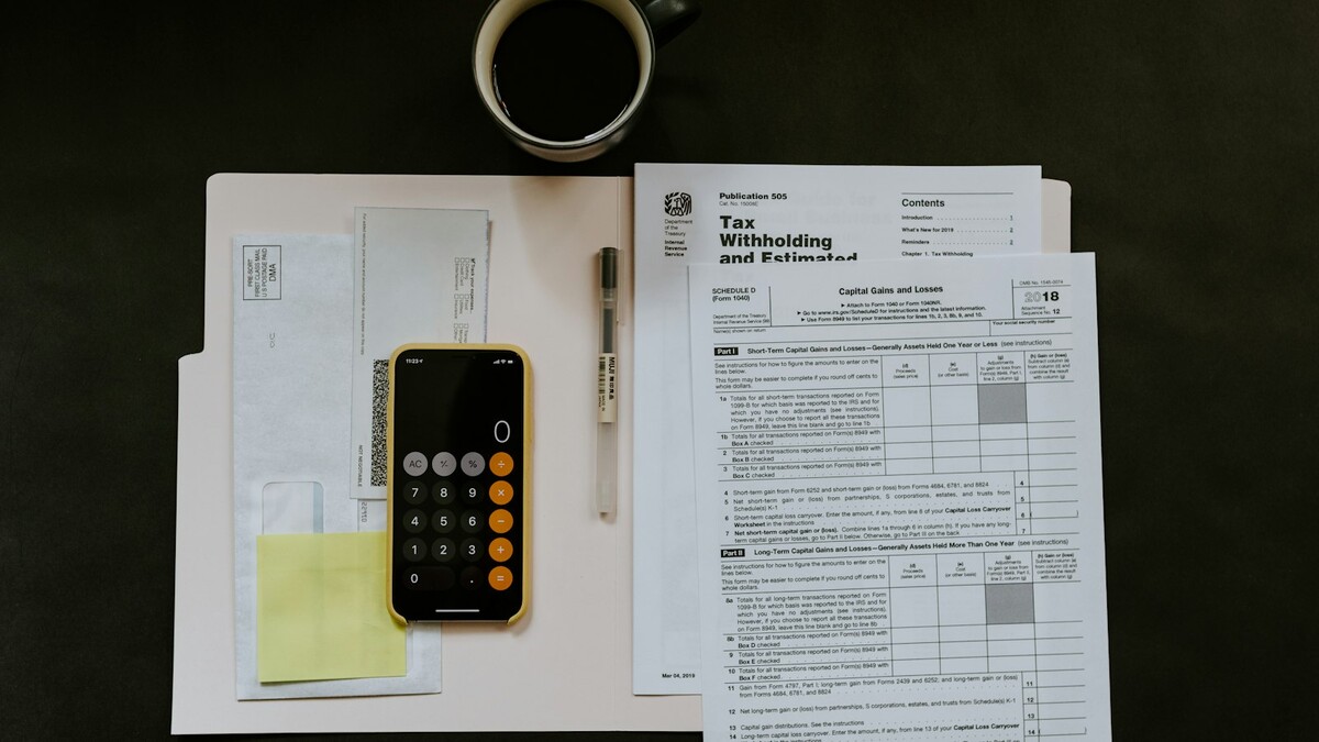 Documentos fiscais, celular com calculadora e caneta sobre uma mesa